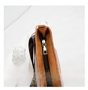 Close-up of smooth metal zipper and colorful vintage patterned strap on brown tote bag