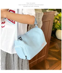 Close-up of a light blue canvas crossbody bag with dual zippers and adjustable strap