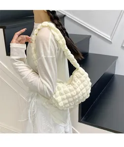 Détail d'un sac bandoulière froncé beige montrant la texture bulle et la fermeture éclair