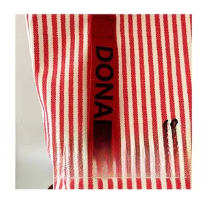 Detailed close-up of striped canvas tote bag showing red woven strap with Donald letters