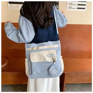 Vue détaillée du sac bandoulière en toile avec coutures contrastées et porte-monnaie