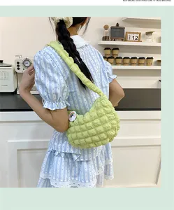 Détail du sac à bandoulière matelassé vert clair avec un badge arc-en-ciel sur le côté