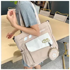 Détail du sac cabas en toile avec poche contrastée, écusson étoile et petit porte-monnaie