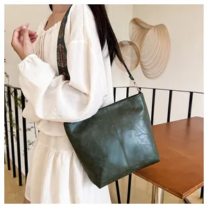 Detail of dark green PU leather tote bag featuring a vintage ethnic pattern wide strap