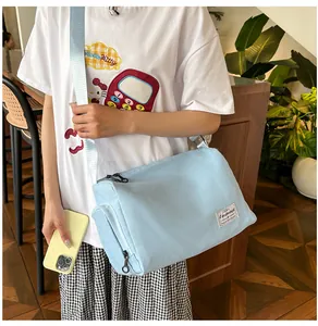 Detail of light blue canvas crossbody bag showing side zipper pocket and logo label