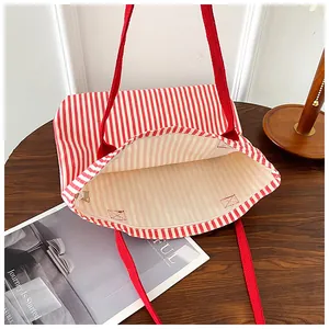 Detailed view of red and white striped canvas tote bag on a dark wooden surface