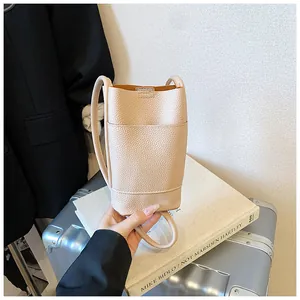 Dettaglio della trama in pelle martellata beige su una mini borsa a secchiello compatta
