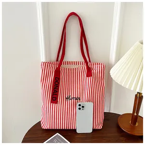 Close-up of red and white striped canvas tote bag with Humin embroidery on wood table