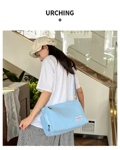 Detail of light blue canvas crossbody bag with adjustable strap and zip pockets