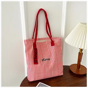 Detail of red and white striped canvas tote bag with Humin embroidery and red handles