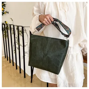Close-up of dark green vintage tote bag featuring a decorative ethnic style wide shoulder strap