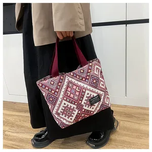 Detail of ethnic woven tote bag with burgundy geometric patterns and fashion fabric label