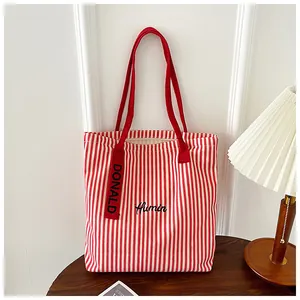 Detail of red and white striped canvas tote bag with Humin embroidery and side label
