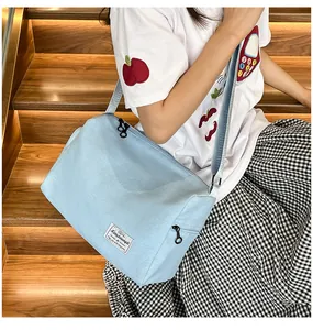 Close-up of light blue canvas bag with woven strap on wooden stairs in warm lighting