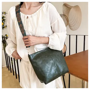 Close-up of a green faux leather tote bag featuring a colorful ethnic jacquard wide strap