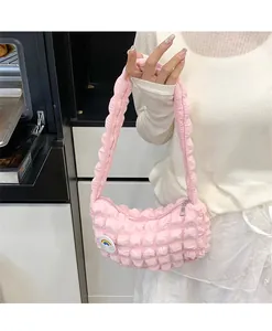 Gros plan du sac nuage plissé rose avec badge arc-en-ciel tenu par un mannequin