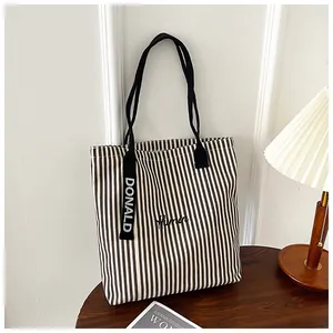 Macro detail of striped canvas tote bag showing black embroidery and Donald ribbon strap