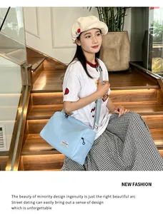Detail of light blue canvas crossbody bag with adjustable strap and side zipper pocket