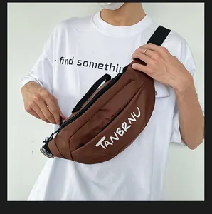 Brown chest bag with TANBRNU print worn by a model against a clean white wall