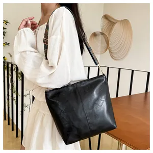 Detail of black PU leather tote with colorful ethnic embroidery wide shoulder strap