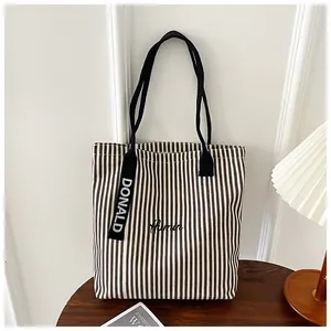 Close-up of striped canvas tote bag with Humor embroidery and Donald ribbon tag detail