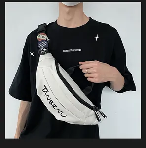 Detail of off-white canvas chest bag with brand text, zippers, and punk-style badges