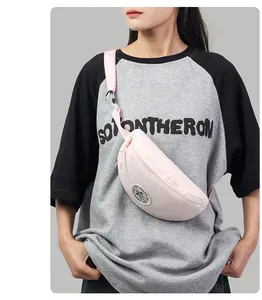 Detail of light pink crescent nylon waist bag featuring round patch and adjustable strap