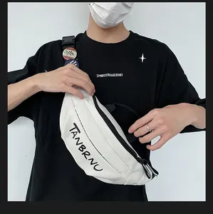 Close-up of white canvas sports chest bag with black TANBRNU print and adjustable strap