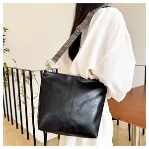 Detail of black vintage tote bag with a textured finish and colorful geometric strap