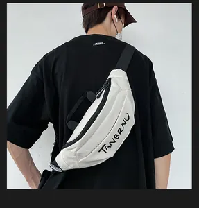 Close-up of white canvas chest bag with black zipper and TANBRNU logo on model