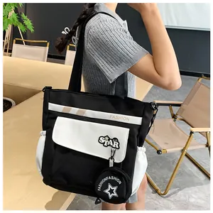 Détail du sac fourre-tout noir et blanc avec poche STAR et pendentif rond