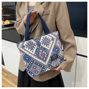 Close-up of ethnic tapestry pattern canvas tote bag with fashion label and blue handles
