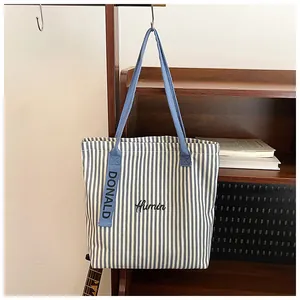 Detailed shot of striped canvas tote bag with blue handles on a wooden background