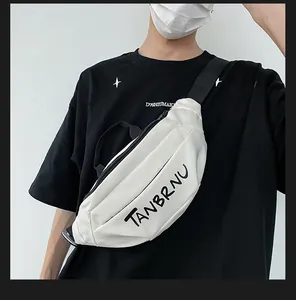 Detail of white nylon crossbody bag featuring black letter print and adjustable strap