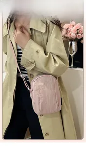 Close-up of lightweight pale pink nylon crossbody bag with adjustable strap and logo detail