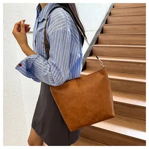Close-up of vintage brown leather tote bag with wide shoulder strap and refined stitching