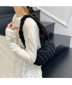 Détail du sac à bandoulière noir à texture popcorn avec bandoulière plissée sur modèle