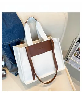 Detail of canvas tote bag with brown leather trim and fashion engraving on sofa