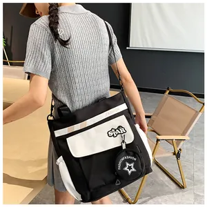 Détail du sac en toile contrasté avec écusson étoile et bandoulière réglable avec charme