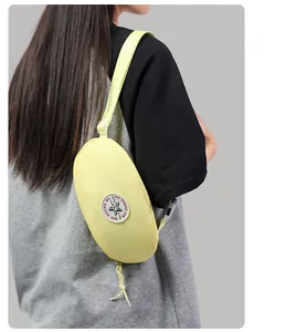 Detail of a light yellow nylon chest bag featuring a round star patch on a model back