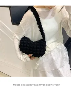 Modèle portant un sac bandoulière noir en tissu popcorn, montrant le style et la coupe