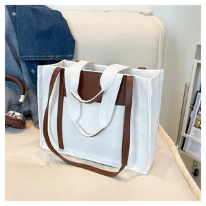 Detail of white canvas tote bag with embossed brown leather patch and dual handles