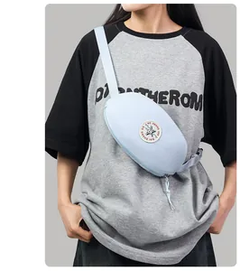 Close-up of light blue sporty chest bag with star patch and adjustable strap on a model