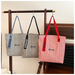 Detailed shot of striped canvas tote bags in blue, brown and red with embroidery