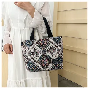 Detailed shot of ethnic woven pattern tote bag with wide black handles on a model