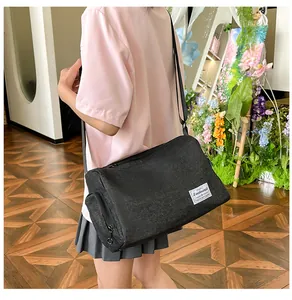 Close-up of black canvas crossbody pillow bag with adjustable strap and brand tag