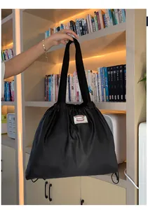 Detailansicht der schwarzen Beuteltasche mit Xiuxian-Logo vor dem Bücherregal