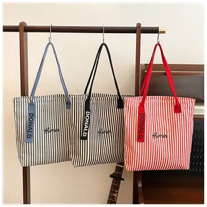 Detail view of striped canvas tote bags with Humin embroidery in blue, black, and red colors