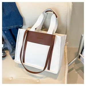 Detail of canvas tote bag with brown leather patch and Fashion Bag embossed logo on sofa
