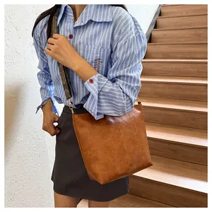 Detailed view of vintage brown crossbody bag with patterned wide strap on a model